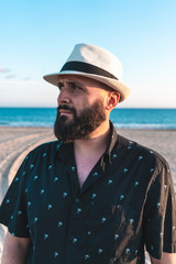 Fototapeta na wymiar Portrait of a man with a beard and a white hat on a beach