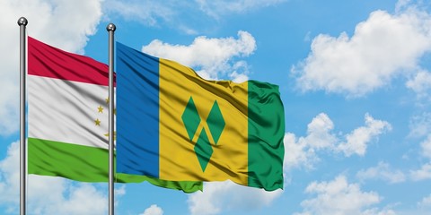 Tajikistan and Saint Vincent And The Grenadines flag waving in the wind against white cloudy blue sky together. Diplomacy concept, international relations.