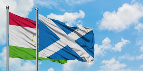 Tajikistan and Scotland flag waving in the wind against white cloudy blue sky together. Diplomacy concept, international relations.