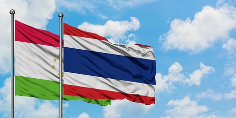 Tajikistan and Thailand flag waving in the wind against white cloudy blue sky together. Diplomacy concept, international relations.