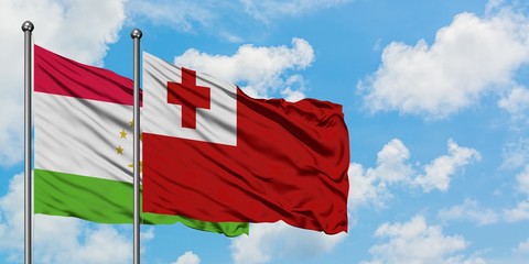 Tajikistan and Tonga flag waving in the wind against white cloudy blue sky together. Diplomacy concept, international relations.