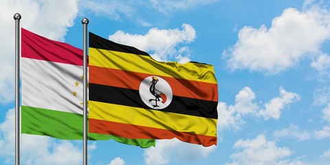 Tajikistan and Uganda flag waving in the wind against white cloudy blue sky together. Diplomacy concept, international relations.