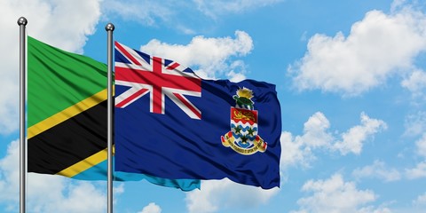 Tanzania and Cayman Islands flag waving in the wind against white cloudy blue sky together. Diplomacy concept, international relations.