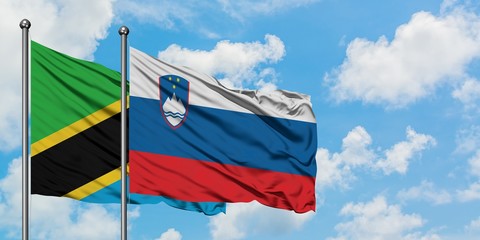 Tanzania and Slovenia flag waving in the wind against white cloudy blue sky together. Diplomacy concept, international relations.