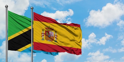Tanzania and Spain flag waving in the wind against white cloudy blue sky together. Diplomacy concept, international relations.