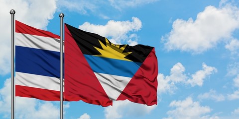 Thailand and Antigua and Barbuda flag waving in the wind against white cloudy blue sky together. Diplomacy concept, international relations.