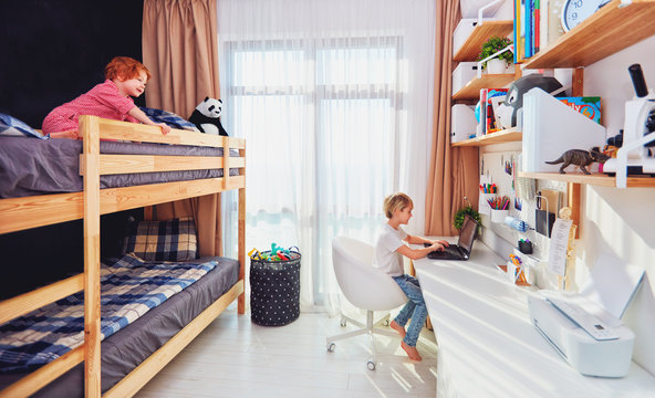 Two Boys, Brothers In Kids Room With Bunk Bed And Wall Shelves