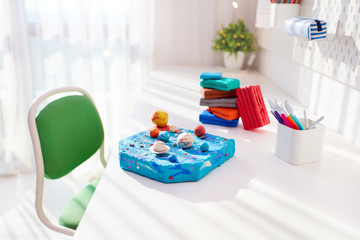 handcrafted solar system made of plasticine by kids, on the desk in the kids room, school project © Olesia Bilkei