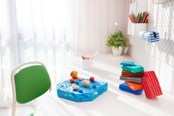 handcrafted solar system made of plasticine by kids, on the desk in the kids room, school project