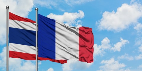 Thailand and France flag waving in the wind against white cloudy blue sky together. Diplomacy concept, international relations.