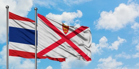 Thailand and Jersey flag waving in the wind against white cloudy blue sky together. Diplomacy concept, international relations.