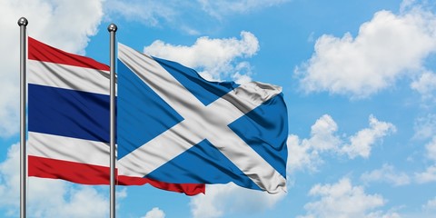 Thailand and Scotland flag waving in the wind against white cloudy blue sky together. Diplomacy concept, international relations.