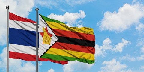 Thailand and Zimbabwe flag waving in the wind against white cloudy blue sky together. Diplomacy concept, international relations.