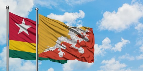 Togo and Bhutan flag waving in the wind against white cloudy blue sky together. Diplomacy concept, international relations.