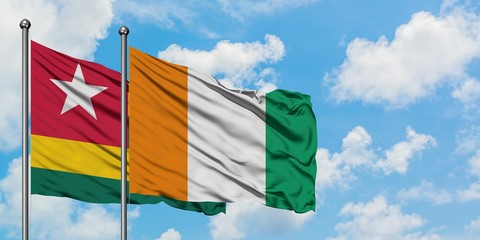 Togo and Cote D'Ivoire flag waving in the wind against white cloudy blue sky together. Diplomacy concept, international relations.