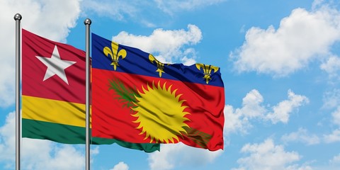 Togo and Guadeloupe flag waving in the wind against white cloudy blue sky together. Diplomacy concept, international relations.
