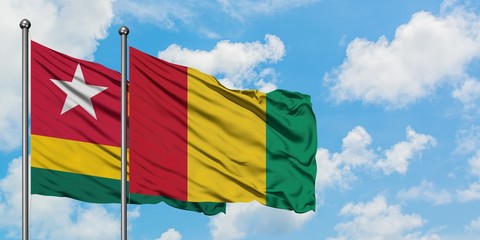 Togo and Guinea flag waving in the wind against white cloudy blue sky together. Diplomacy concept, international relations.