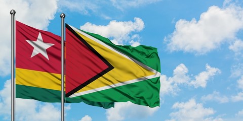 Togo and Guyana flag waving in the wind against white cloudy blue sky together. Diplomacy concept, international relations.