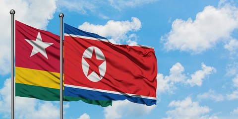 Togo and North Korea flag waving in the wind against white cloudy blue sky together. Diplomacy concept, international relations.