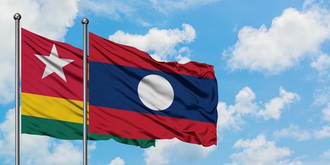 Togo and Laos flag waving in the wind against white cloudy blue sky together. Diplomacy concept, international relations.