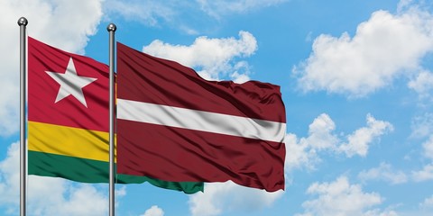 Togo and Latvia flag waving in the wind against white cloudy blue sky together. Diplomacy concept, international relations.