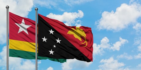 Togo and Papua New Guinea flag waving in the wind against white cloudy blue sky together. Diplomacy concept, international relations.