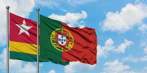 Togo and Portugal flag waving in the wind against white cloudy blue sky together. Diplomacy concept, international relations.