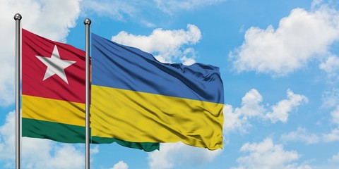 Togo and Ukraine flag waving in the wind against white cloudy blue sky together. Diplomacy concept, international relations.