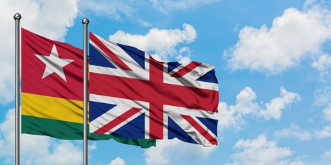 Togo and United Kingdom flag waving in the wind against white cloudy blue sky together. Diplomacy concept, international relations.