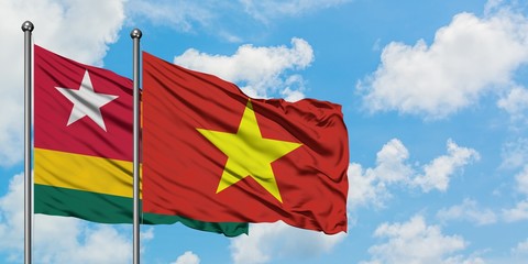 Togo and Vietnam flag waving in the wind against white cloudy blue sky together. Diplomacy concept, international relations.