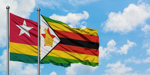 Togo and Zimbabwe flag waving in the wind against white cloudy blue sky together. Diplomacy concept, international relations.