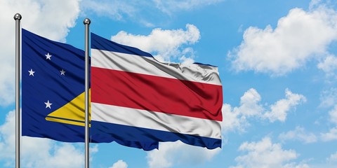 Tokelau and Costa Rica flag waving in the wind against white cloudy blue sky together. Diplomacy concept, international relations.