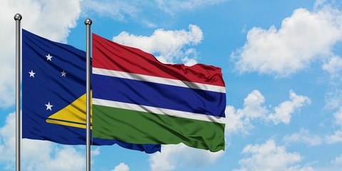 Tokelau and Gambia flag waving in the wind against white cloudy blue sky together. Diplomacy concept, international relations.