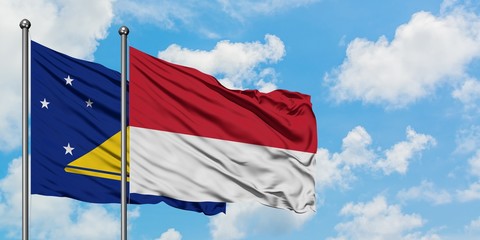 Tokelau and Monaco flag waving in the wind against white cloudy blue sky together. Diplomacy concept, international relations.