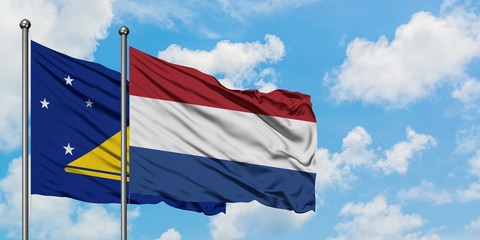 Tokelau and Netherlands flag waving in the wind against white cloudy blue sky together. Diplomacy concept, international relations.