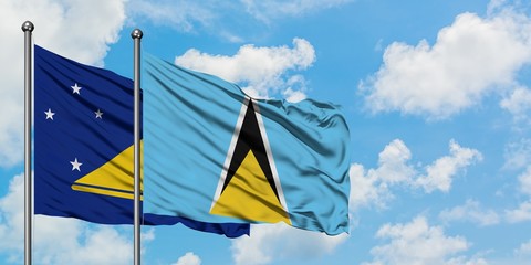 Tokelau and Saint Lucia flag waving in the wind against white cloudy blue sky together. Diplomacy concept, international relations.