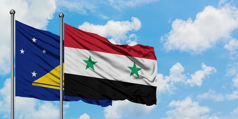 Tokelau and Syria flag waving in the wind against white cloudy blue sky together. Diplomacy concept, international relations.