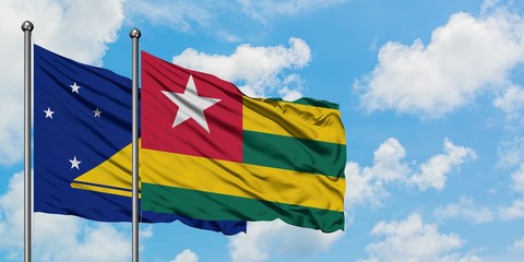 Tokelau and Togo flag waving in the wind against white cloudy blue sky together. Diplomacy concept, international relations.