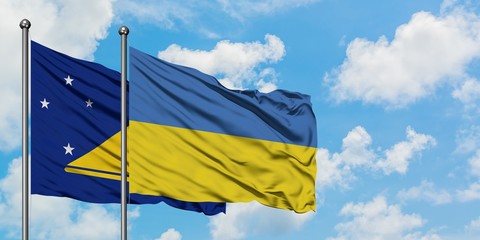 Tokelau and Ukraine flag waving in the wind against white cloudy blue sky together. Diplomacy concept, international relations.