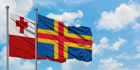 Tonga and Aland Islands flag waving in the wind against white cloudy blue sky together. Diplomacy concept, international relations.