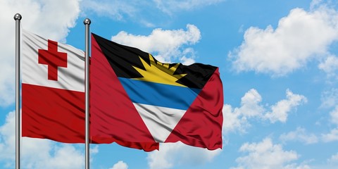 Tonga and Antigua and Barbuda flag waving in the wind against white cloudy blue sky together. Diplomacy concept, international relations.