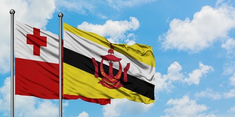 Tonga and Brunei flag waving in the wind against white cloudy blue sky together. Diplomacy concept, international relations.