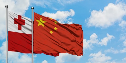 Tonga and China flag waving in the wind against white cloudy blue sky together. Diplomacy concept, international relations.