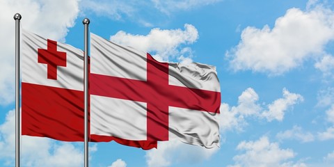 Tonga and England flag waving in the wind against white cloudy blue sky together. Diplomacy concept, international relations.