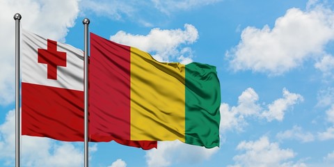 Tonga and Guinea flag waving in the wind against white cloudy blue sky together. Diplomacy concept, international relations.