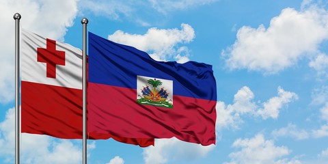 Tonga and Haiti flag waving in the wind against white cloudy blue sky together. Diplomacy concept, international relations.