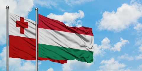 Tonga and Hungary flag waving in the wind against white cloudy blue sky together. Diplomacy concept, international relations.