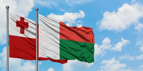 Tonga and Madagascar flag waving in the wind against white cloudy blue sky together. Diplomacy concept, international relations.