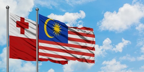 Tonga and Malaysia flag waving in the wind against white cloudy blue sky together. Diplomacy concept, international relations.