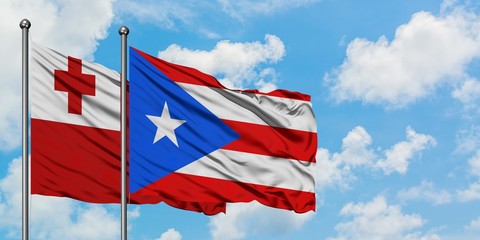 Tonga and Puerto Rico flag waving in the wind against white cloudy blue sky together. Diplomacy concept, international relations.